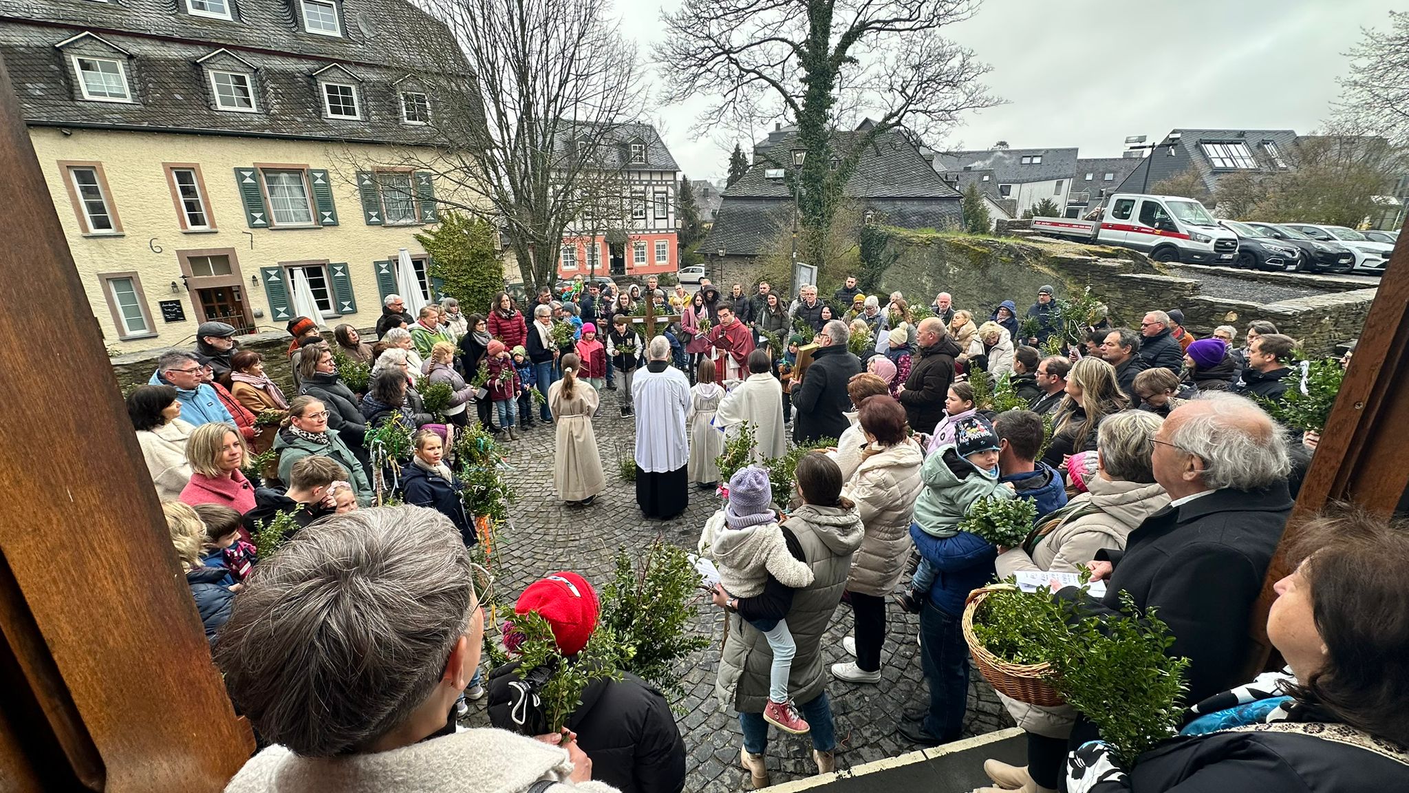 Die Gemeinde ist zur Palmweihe auf dem Kirchenvorplatz versammelt.